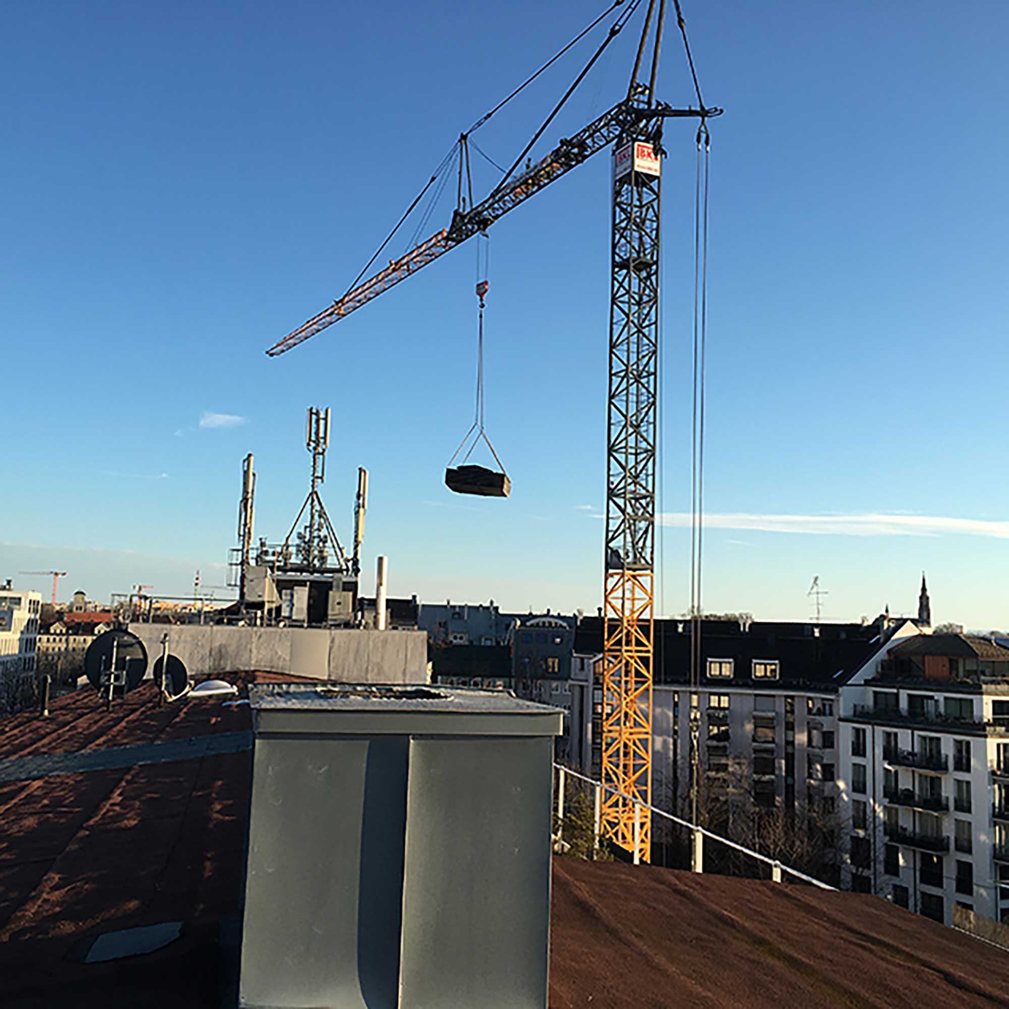 BKL bottom-slewing crane during lifting operations over the roofs of a city construction site under a blue sky
