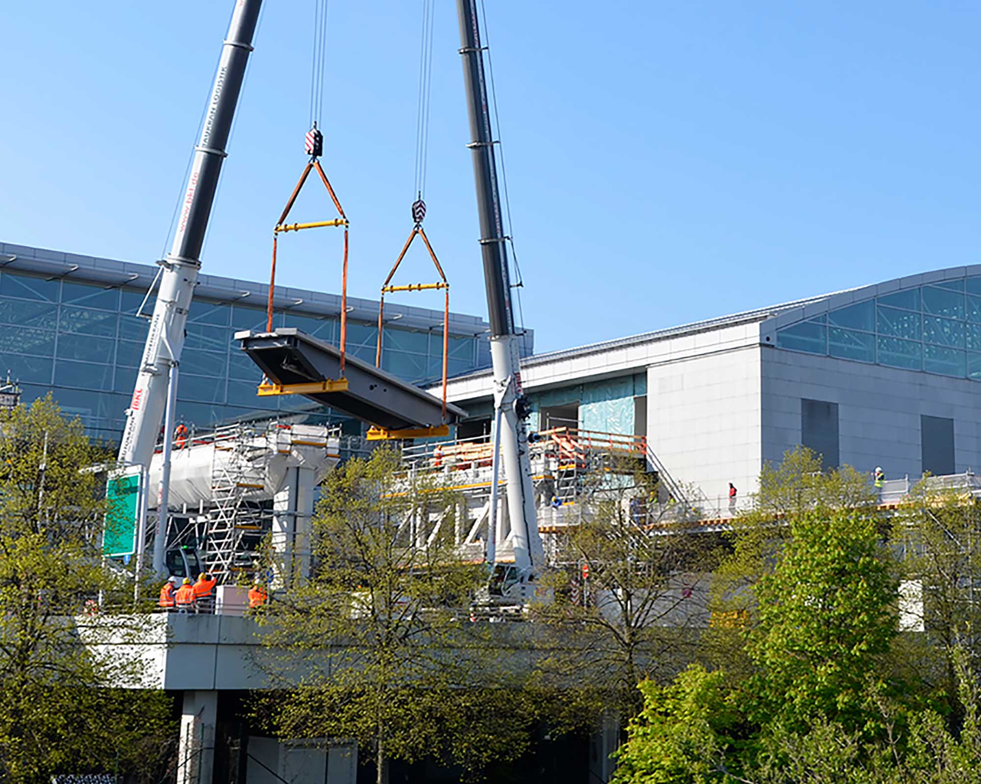 Bild aus den BKL Referenzen: Zwei BKL Autokrane beim Tandemhub eines schweren Bauteils für das Personentransportsystem am Flughafen Frankfurt Terminal 3
