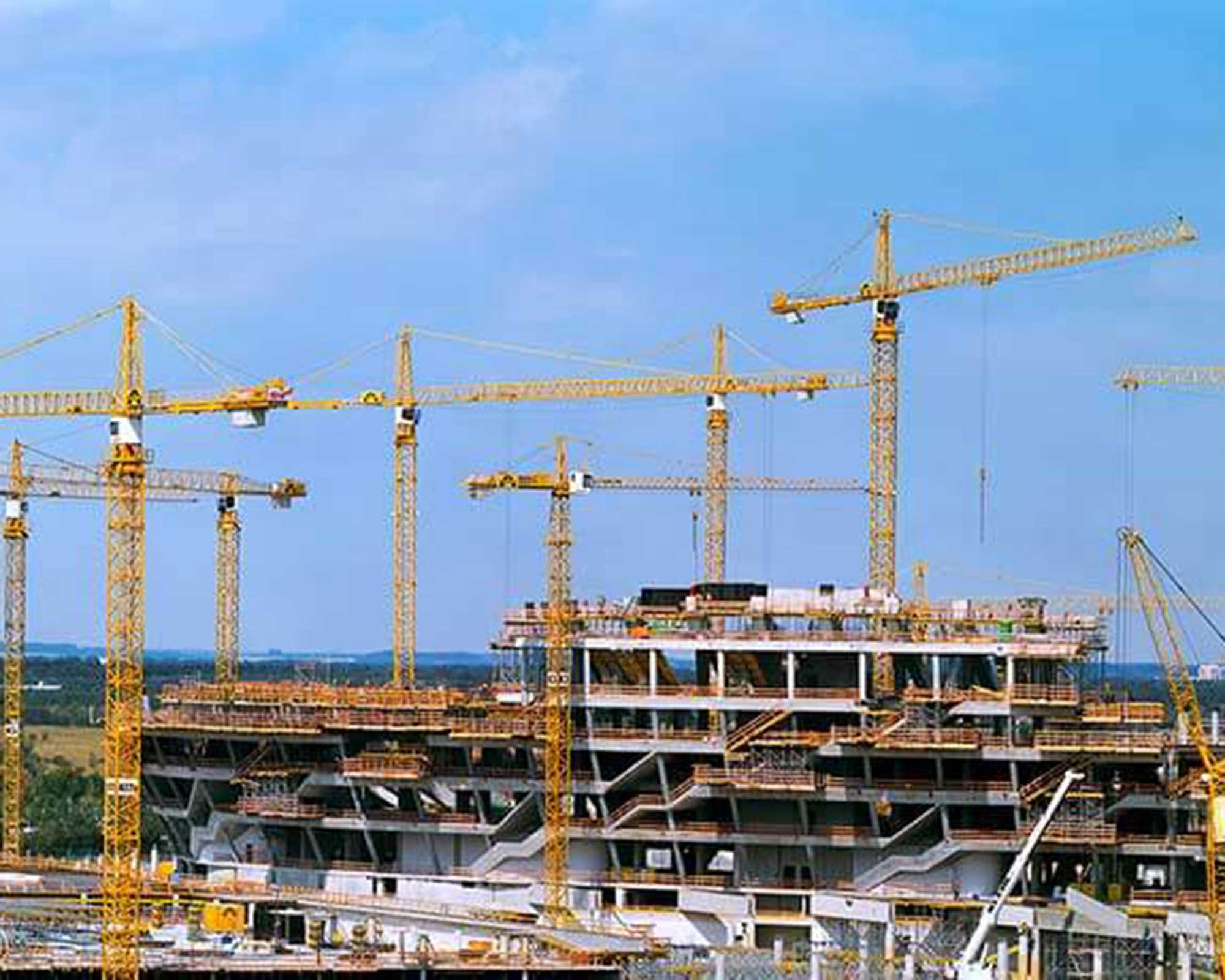 BKL Referenz für die Allianz Arena: Mehrere gelbe Turmdrehkrane von BKL im Einsatz auf der Großbaustelle des Rohbaus der Allianz Arena in München, Kraneinsatz im 24-Stunden-Betrieb.