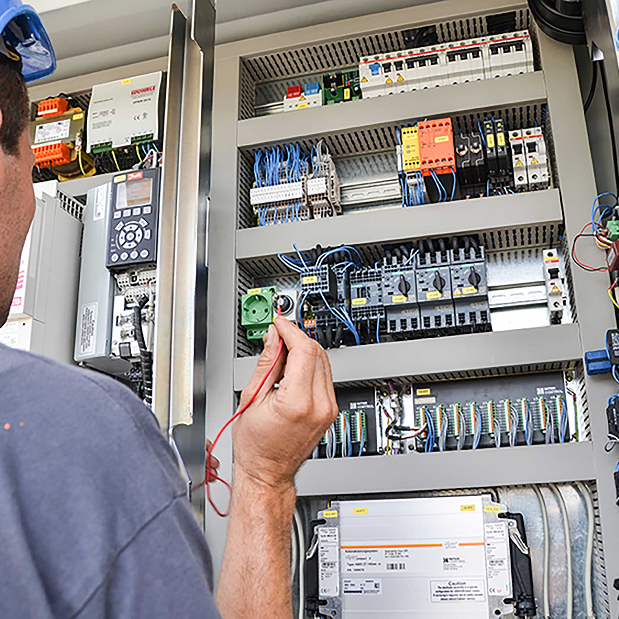Ein BKL Kranservice Techniker prüft eine elektrische Schaltanlage für die Kranreparatur oder Kranwartung eines Baukrans.