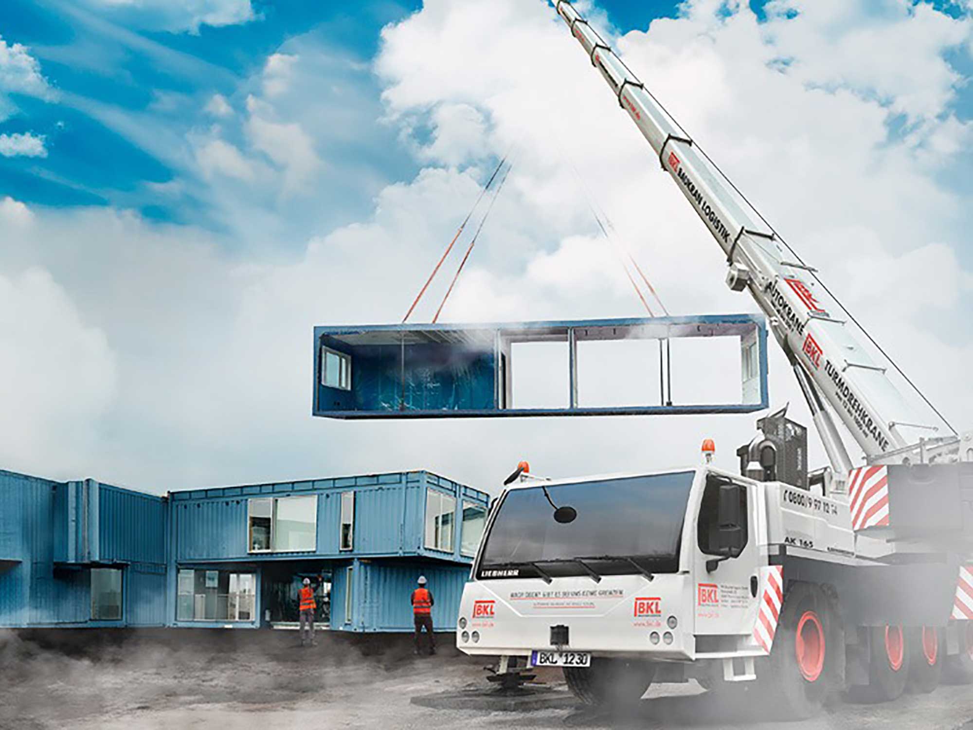 Ein BKL Kran hebt präzise einen blauen modularen Container mit Fenstern zum Aufbau einer Gebäudestruktur, ein Beispiel für effiziente Containermontage mit dem BKL Service.