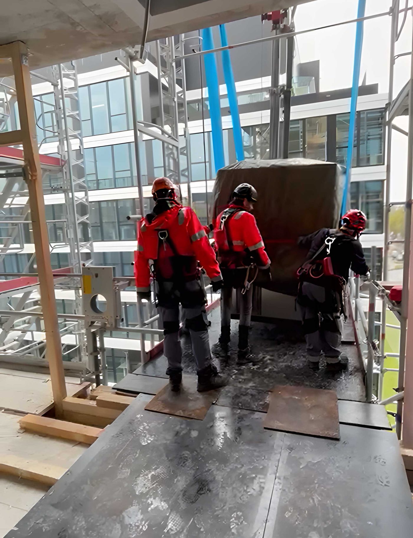 Drei Fachkräfte von BKL Industriemontage bei der präzisen Schwerlastmontage, die eine große Maschine auf einer Montageplattform bewegen und positionieren für LG Electronics