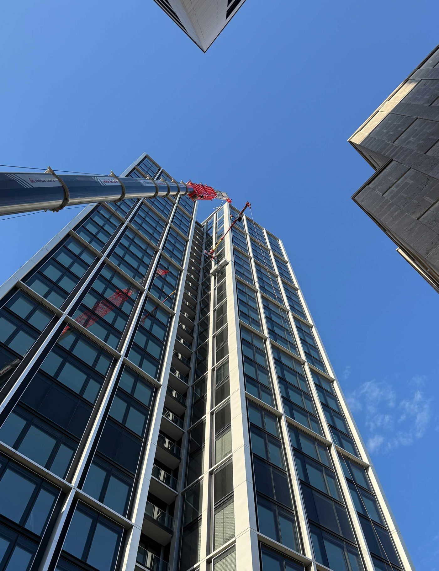 Liebherr LTM 1230-5.1 Autokran von BKL mit Gitterverlängerung bei der präzisen Glasmontage am WINX Tower Frankfurt in 97 Metern Höhe.