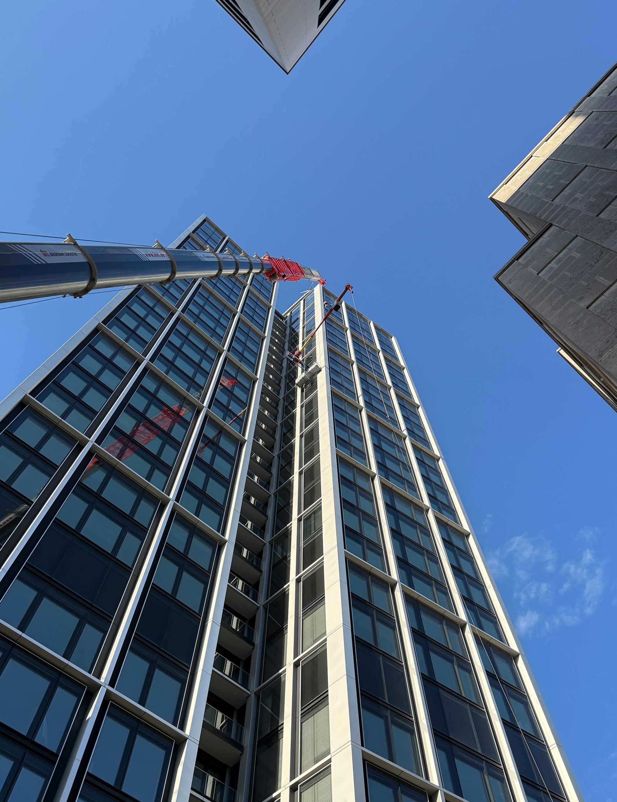 Liebherr LTM 1230-5.1 Autokran von BKL mit Gitterverlängerung bei der präzisen Glasmontage am WINX Tower Frankfurt in 97 Metern Höhe.