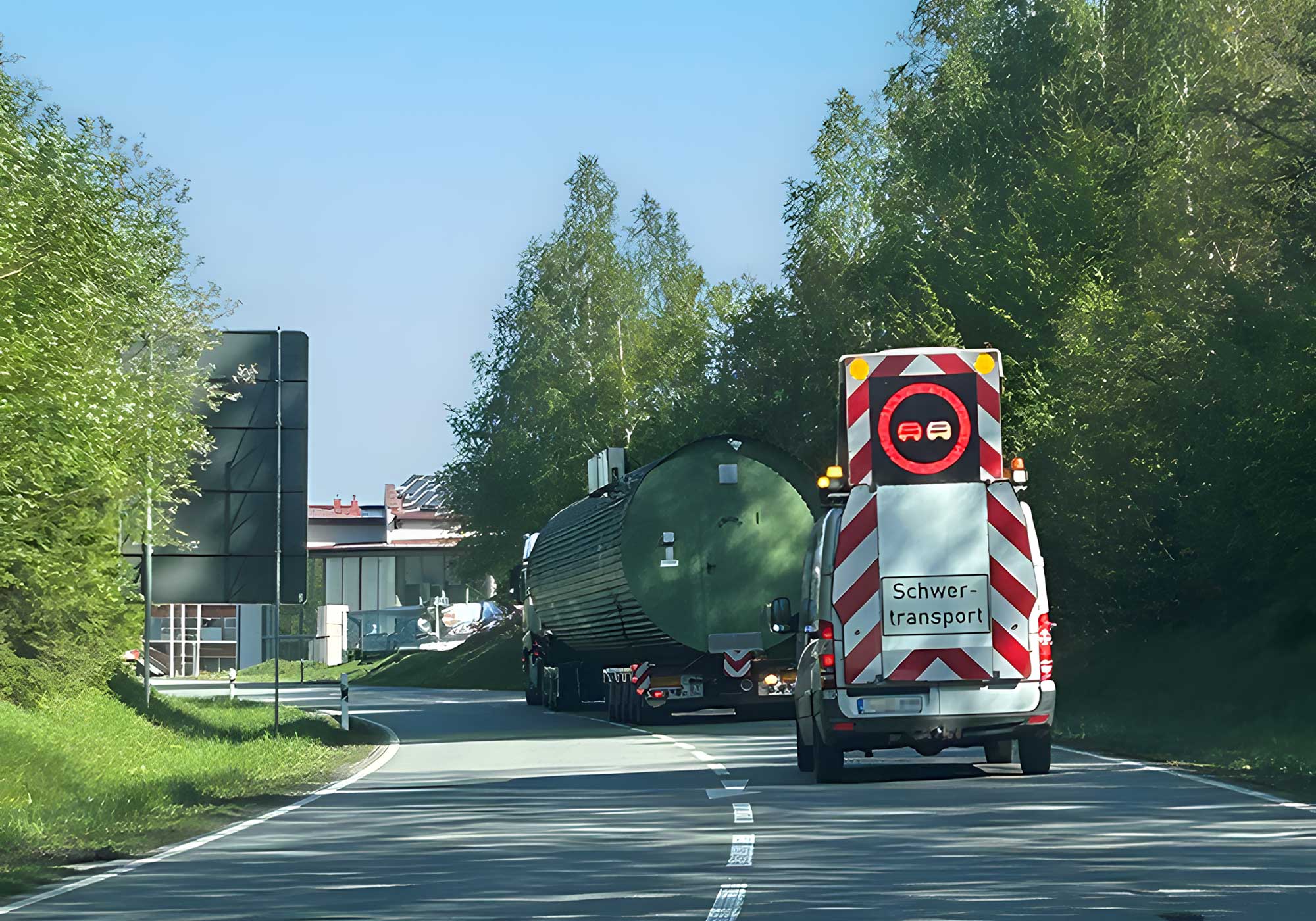 A heavy transport on the road with BF3 escort vehicle including BF3 driver and large-volume load as part of the BKL transport services.