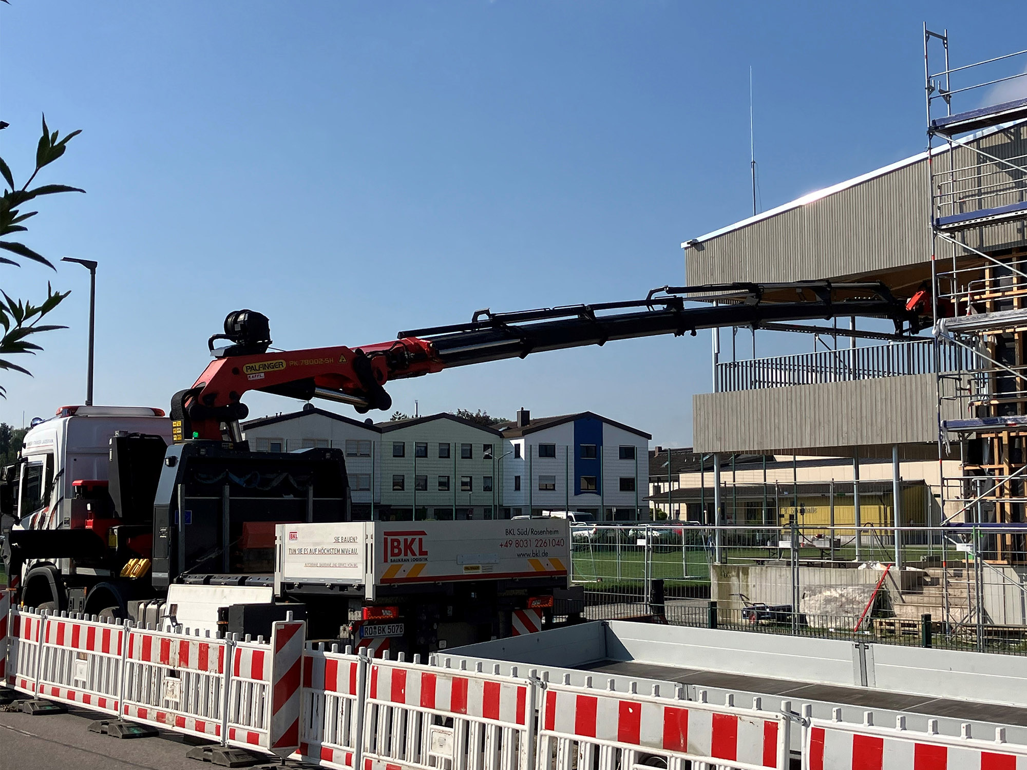 Truck with loader crane from BKL as a 2-in-1 solution for transport and crane work, supported loader crane in use for fast lifting work on the construction site.