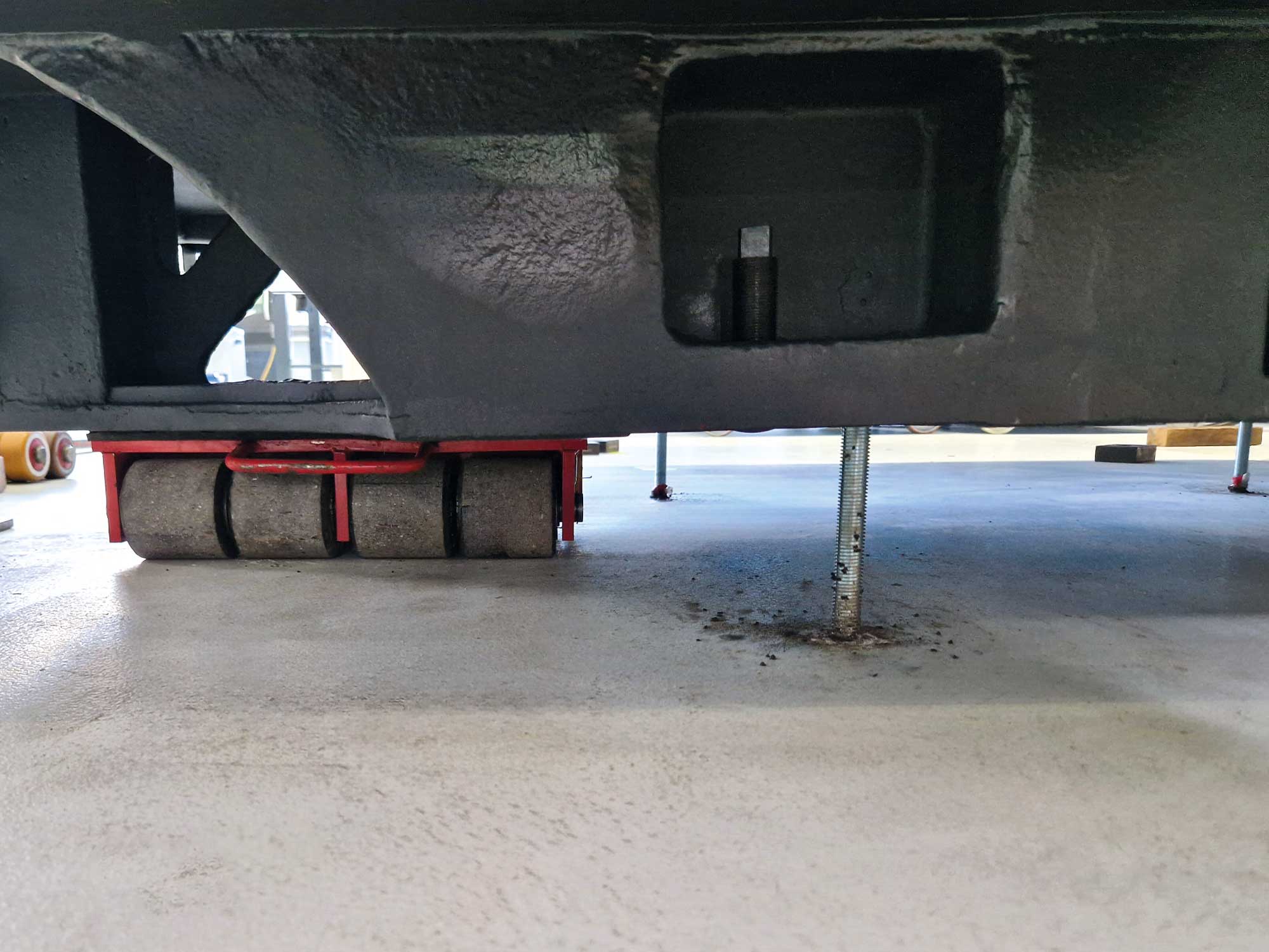 Eine schwere Maschinenkomponente auf Schwerlastrollen und Nivellierstützen wird für einen präzisen Maschinentransport oder eine Anlagenmontage von BKL Industriemontage positioniert.