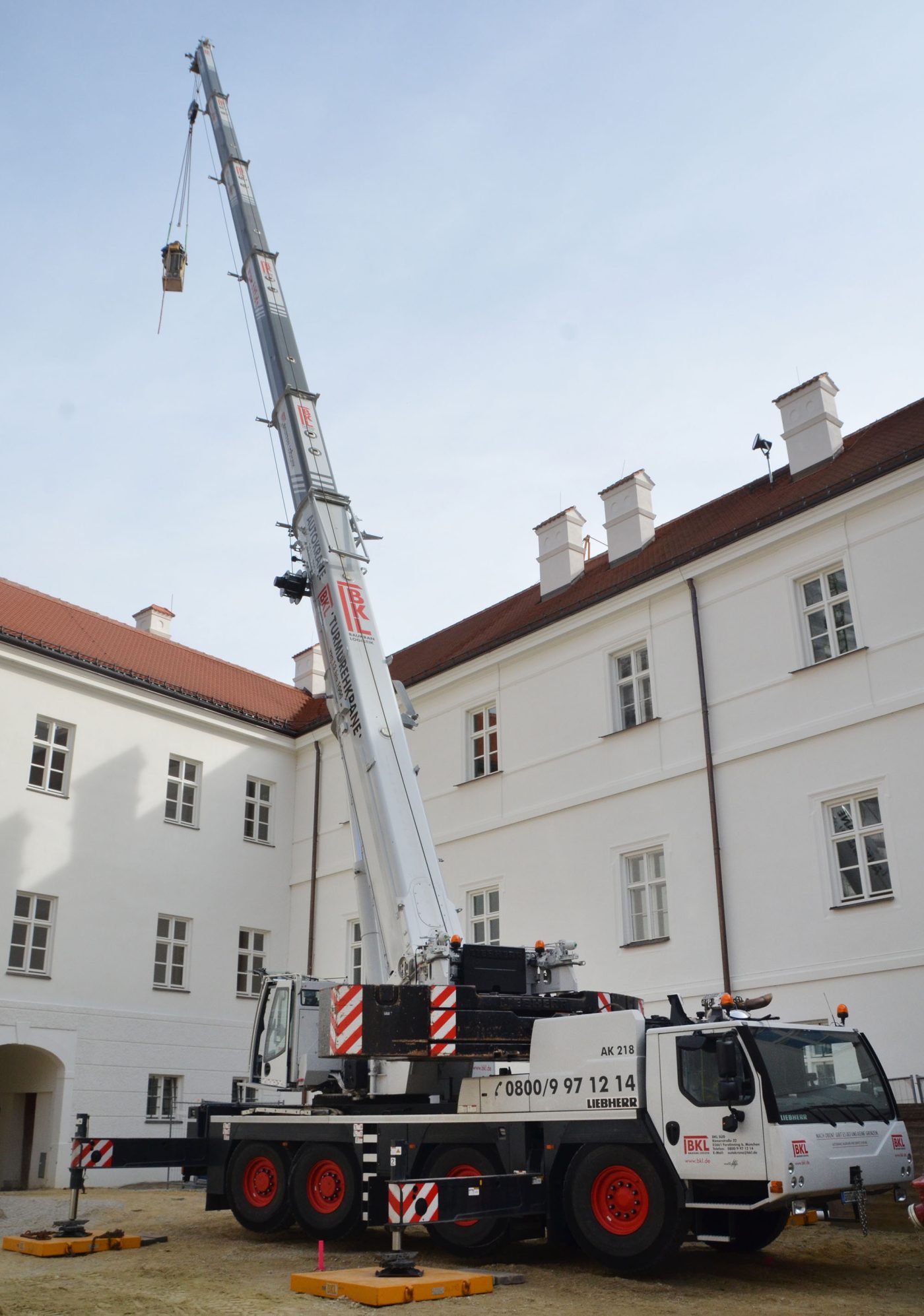 BKL Autokran LTM 1120-4.1 bei Hebearbeiten in einem Innenhof