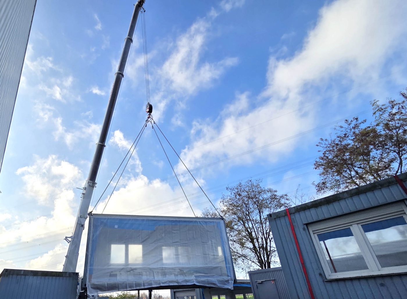 BKL Autokran LTF 1060-4.1 hebt einen verpackten Container für den Containertransport bei Wind und Wetter