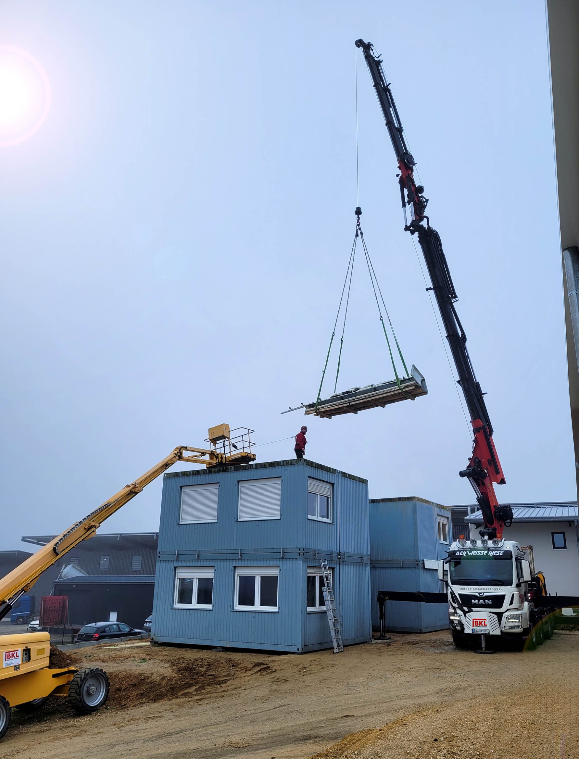Ein Ladekran PK 92002 SH und eine Gelenkteleskopbühne von BKL bei der Montage einer Containeranlage