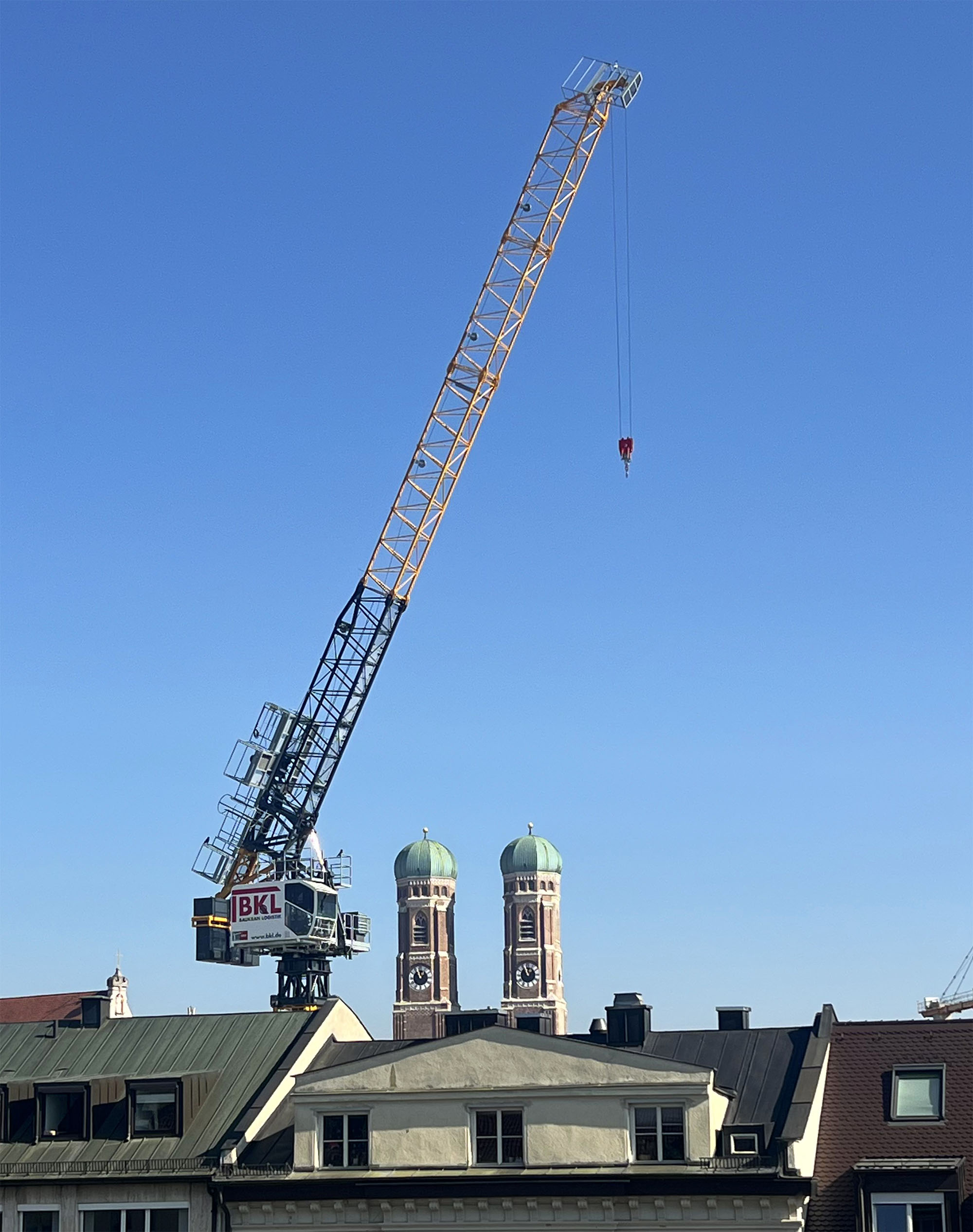 BKL Sáez jib crane against a blue sky during lifting operations in Munich city center