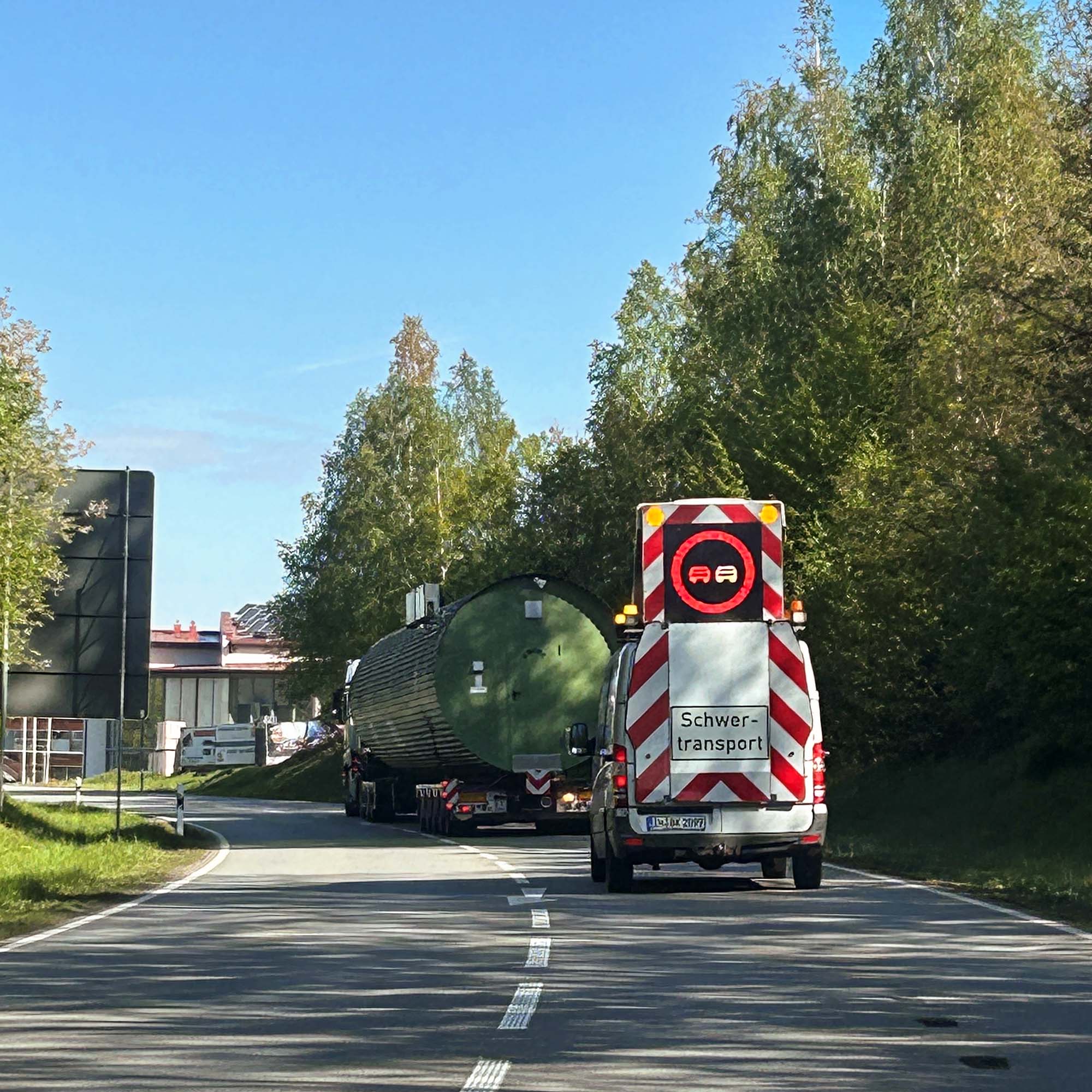 A heavy transport on the road with BF3 escort vehicle including BF3 driver and large-volume load as part of the BKL transport services.